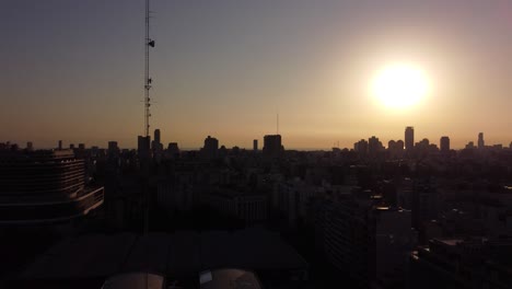 Aerial-shot-showing-silhouette-of-skyscraper-buildings-and-tv-televion-antenna-during-Sunrise
