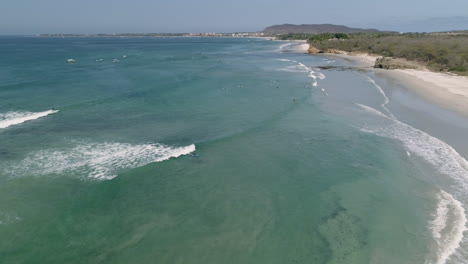 Umlaufende-Antenne,-Während-Der-Surfer-Eine-Welle-An-Der-Wunderschönen-Blauen-Pazifikküste-Fängt,-4k