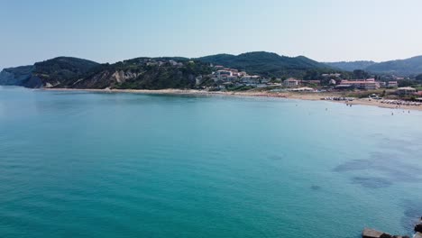 Greek-island-bay,-aerial-drone-view-of-people-swimming-and-sunbathing-on-beach-in-San-Stefanos-Corfu