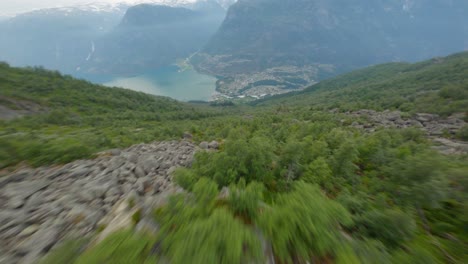 Aerial-fpv-flight-downhill-green-mountains-towards-famous-tourist-town-Odda-and-Fjord-in-Valley