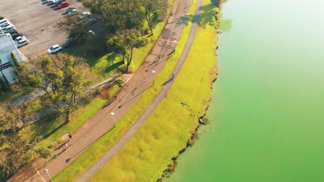 Radfahrer-Fahren-Auf-Dem-Parque-Barigui,-Gefolgt-Von-Einer-Drohnen-Luftaufnahme,-Curitiba,-Paraná,-Brasilien