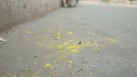 Close-up-of-dirty-feet-of-poor-dark-skin-Indian-girl-walking-away,-yellow-powder-on-feet-and-ground,-holi-festival