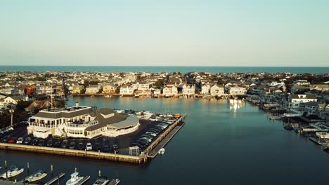 Drone-backing-up-over-Harbor-in-Stoneharbor,-New-Jersey-during-golden-hour