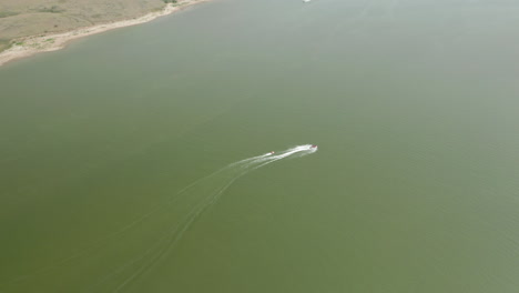 Aerial-view-of-speedboat-pulling-inner-tubers-at-Saskatchewan-Landing,-Canada