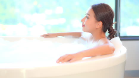 Close-up-of-a-beautiful,-young,-healthy-woman-relaxes-in-a-luxurious-spa-like-bathtub-full-of-soothing-bubbles