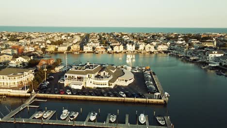 Ariel-closing-in-on-harborfront-restaurant-in-Stone-Harbor,-New-Jersey-during-golden-hour