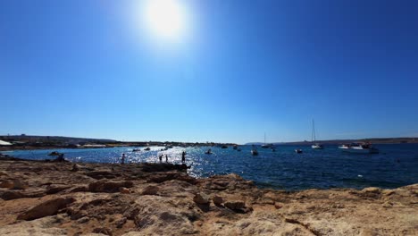 Malta,-Pequeña-Bahía-Armada,-Video-De-Lapso-De-Tiempo-Desde-La-Costa-Con-Pescadores-Y-Bañistas-En-Una-Soleada-Tarde-De-Verano