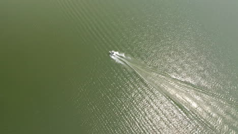 Aerial-arc-above-motorboat-speeding-across-water,-Saskatchewan-Landing,-Canada