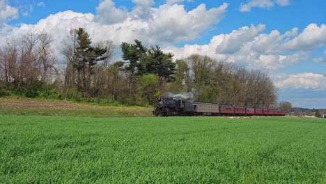 View-of-a-Steam-Passenger-Train-Approaching-Blowing-Smoke-and-Steam-on-a-Beautiful-Spring-Day