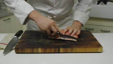 Chef-Preparando-Salmón-Fresco-En-Tabla-De-Madera,-Cortando-Con-Cuchillo,-De-Cerca