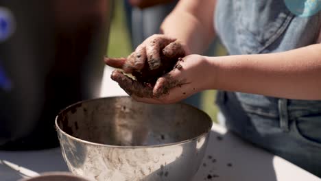 Close-up-of-person-making-a-seed-bomb-above-an-iron-bowl