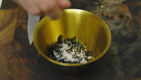 Chef-adding-grains-of-salt-into-bowl-with-seaweed