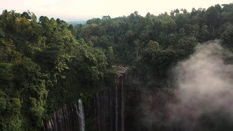 Blick-Von-Oben,-Atemberaubende-Luftaufnahmen-Der-Wasserfälle-Von-Tumpak-Sewu-Coban-Sewu-Mit-Einem-Vulkan-Im-Hintergrund