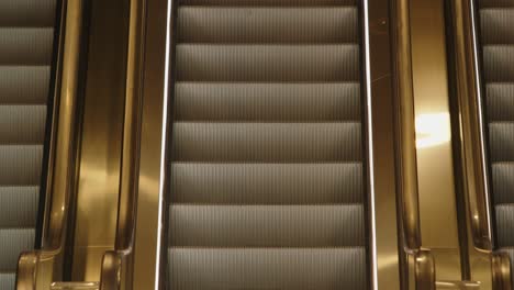 Empty-Escalator-in-Motion,-Gold-and-Silver-Lighting,-Fixed-Static-Shot