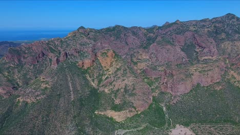 Forward-Aerial-View-of-Dramatic-Desert-Mountain-Landscape-and-High-Shear-Cliffs