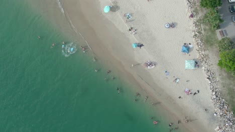 NOOSA-HEADS,-AUSTRALIA---Vertical-aerial-shot-of-holiday-makers-and-tourists-enjoying-noosa-beach-on-queensland's-sunshine-coast