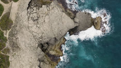 Top-Down-View-Of-Foamy-Waves-Crashing-On-Rocky-Cliffs-At-Cueva-del-Indio-In-Las-Piedras,-Puerto-Rico---aerial-drone-shot