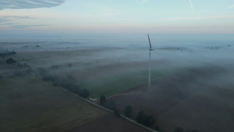 Mysteriöse-Luftaufnahme-Einer-Windmühle-Auf-Einem-Landwirtschaftsfeld-Mit-Mystischem-Nebel,-Europa