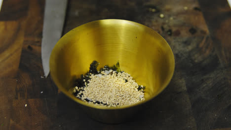 Chef-adding-sesame-into-bowl-with-seaweed-and-salt-for-tasty-sauce,close-up