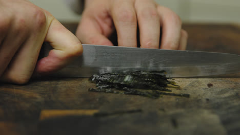 Close-up-shot-of-male-chef-cutting-seaweed-on-wooden-board,slow-motion