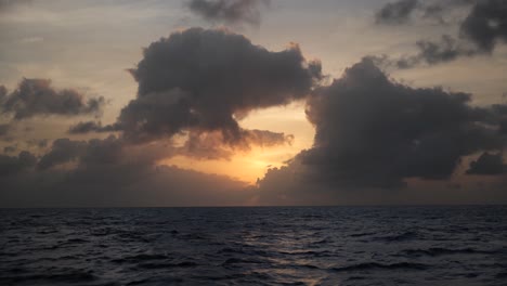 Sun-setting-behind-clouds-above-the-ocean-in-4k