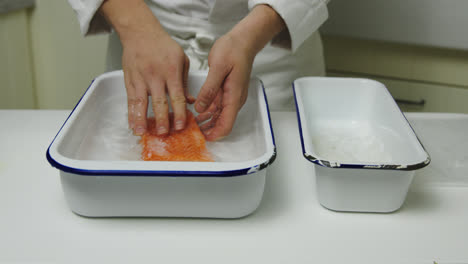 Male-chef-giving-fresh-salmon-fillet-salt-bath-for-delicious-taste,close-up