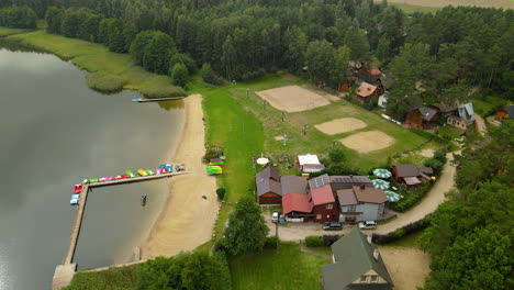 Aerial-view-of-Hartowiec-Lake-with-sandy-beach-and-houses-in-Poland