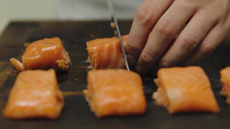 Close-up-slow-motion-of-male-chef-cutting-salmon-fillet-in-small-pieces-with-sharp-knife