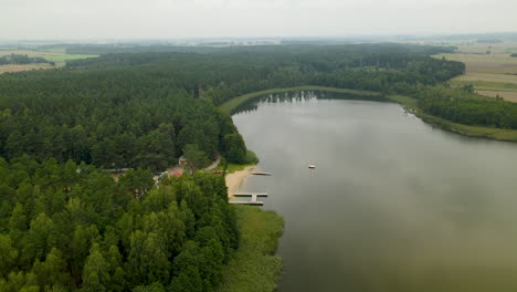 Hartowiec-Lake-with-Dense-Green-Forest-and-Multiple-Wooden-Jetties-in-Lakefront-for-Family-Water-Sports-Activities,-Poland