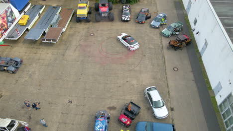 Aerial-View-Men-Filming-A-Car-Drifting-Around-In-Circle-With-Marks-Of-Burnt-Rubber-Tires-And-Smoke