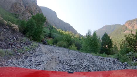 POV-following-a-Jeep-on-gravel-covered-Alpine-Loop-Trail-cut-into-the-mountain-side-of-the-San-Juan-Mountains-in-Colorado