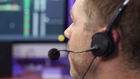 Unrecognizable-man-in-technical-support-talking-on-phone-headset-at-trading-broker-desk