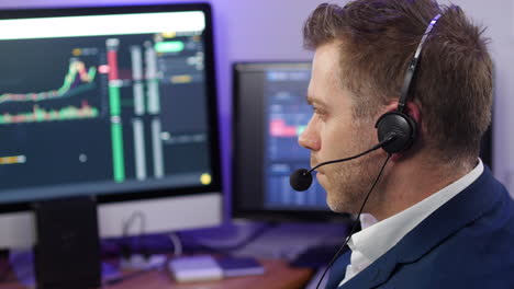 Nodding-man-in-business-clothing-working-in-technical-support-at-a-trading-broker-desk-with-computers