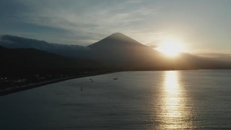Silhouette-of-Mount-Agung-volcano-during-sunset,-Bali-shore,-aerial