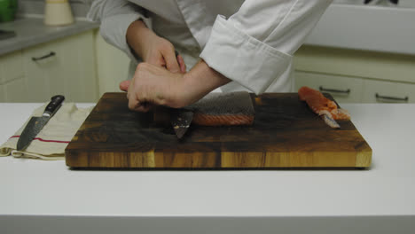 Male-Chef-cutting-of-skin-of-fresh-salmon-fillet-in-luxury-restaurant-kitchen