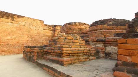 Ancient-Stone-Walls-with-Red-Bricks-at-the-Archaeological-Buddhist-Remains-of-Sarnath,-Varanasi,-India-with-Low-Dolly-Walking-Shot