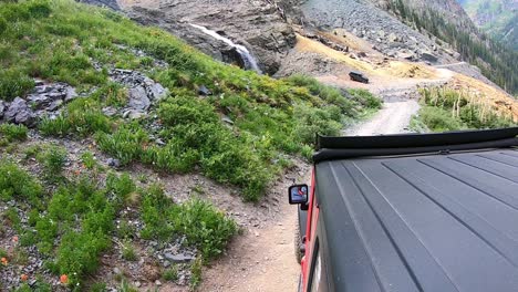 POV-from-roof-of-4WD-vehicle-on-Black-Bear-trail-past-a-waterfall-in-the-San-Juan-Mountains-near-Telluride-Colorado