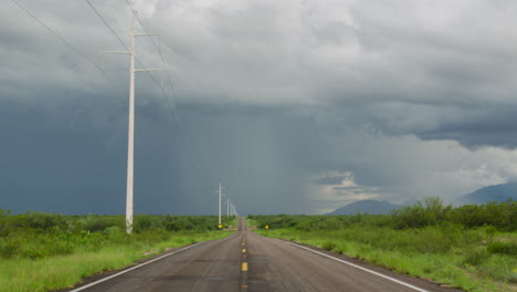 Road-leading-into-the-distance-with-monsoon-rain-and-storm-clouds,-time-lapse