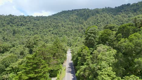 Drohne-Luftaufnahmen-Einer-Geraden,-Einsamen,-Leeren-Straße-Inmitten-Eines-Dichten-Regenwaldes-Während-Bewölkter-Tageszeiten-Ohne-Verkehr-In-Guatemala
