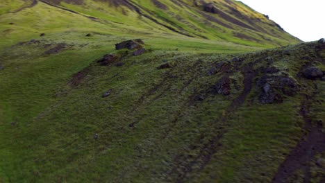 FPV-Of-Green-Hilly-Slopes-With-Flowing-River-At-Seljavallalaug-In-Southern-Iceland