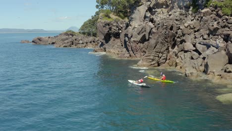 Two-kayakers-paddling-along-shore-of-Moutohora-Whale-Island,-scenic-New-Zealand