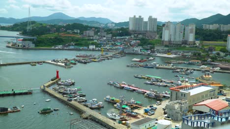 Barcos-De-Amarre-En-El-Puerto-Deportivo-Con-El-Paisaje-Urbano-De-Fondo-De-La-Isla-De-Geojedo-En-Gyeongsangnam-do,-Corea-Del-Sur