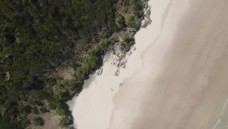 4K-Drohne-Zoomt-Langsam-Aus-Zwei-Menschen-Heraus,-Die-An-Einem-Einsamen-Inselstrand-In-Australien-Liegen