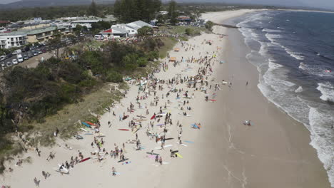 4k-Drone-orbiting-shot-of-people-protesting-on-the-beautiful-beach-against-norwegian-oil-company,-Equinor,-at-Byron-Bay,-New-South-Wales,-Australia---2019