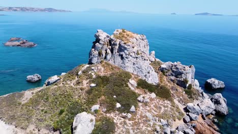 Filmische-Luftaufnahme-Einer-Felsformation-Auf-Einer-Paradiesischen-Griechischen-Insel-Mit-Einer-Kleinen-Kirche-Darauf