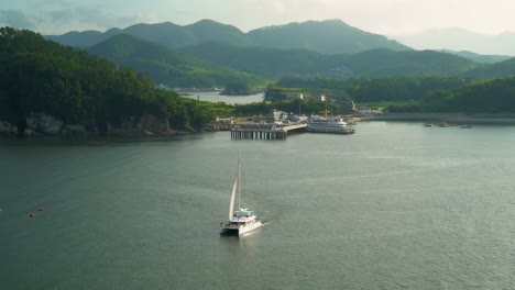 Barco-Turístico-Navegando-Cerca-Del-Hotel-Y-Puerto-Catamarán-Belvedere-En-La-Ciudad-De-Geonje,-Corea-Del-Sur---Plano-Amplio