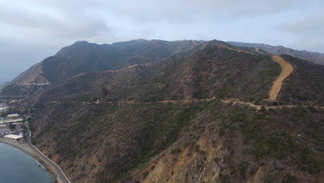 Aerial-View-to-Hills-Trail,-Ridge,-Cloudy-Sky-and-Avalon-Industrial-Park,-Catalina