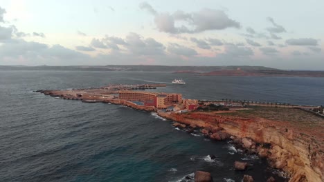 Aerial-drone-video-from-north-of-Malta,-Cirkewwa-ferry-port-at-late-afternoon-with-Comino-and-Gozo-in-the-background