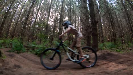 Kid-on-forest-mountain-bike-track-pumping-speed-on-bicycle,-bright-light-rays