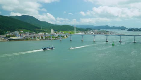 Boats-Sailing-In-The-Blue-Ocean-Towards-Bridge-In-Geojedo-Island,-South-Korea